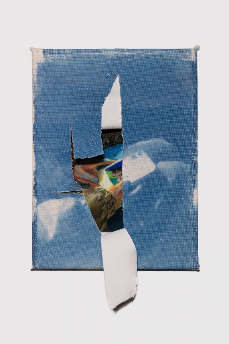 a blue and white torn cyanotype of a person holding what is reveled underneath to be a cellphone